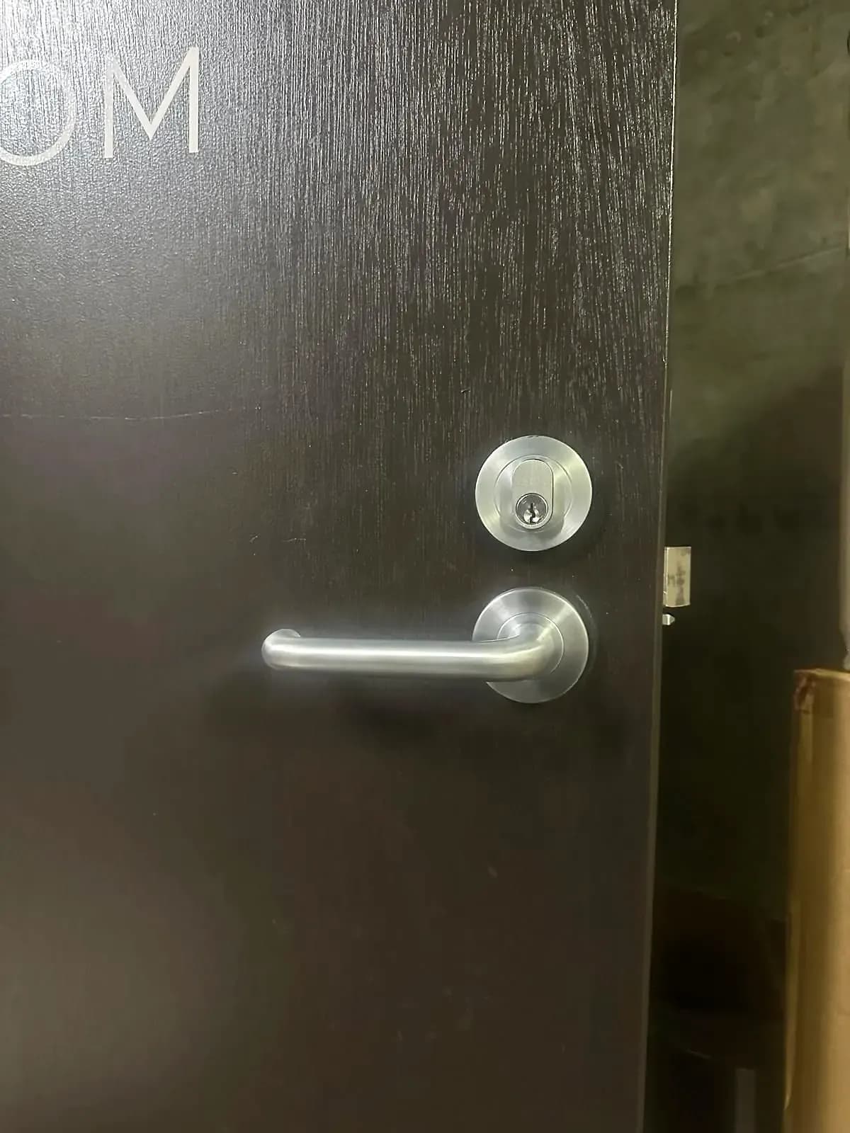 A stainless lever handle and a keyed deadlock fitted to a dark timber office door