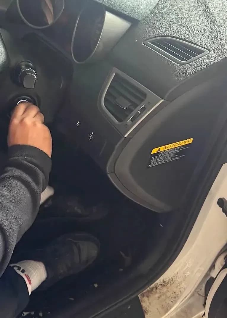 A hand turning a new key in the ignition of a Hyundai, seen from the open driver’s door