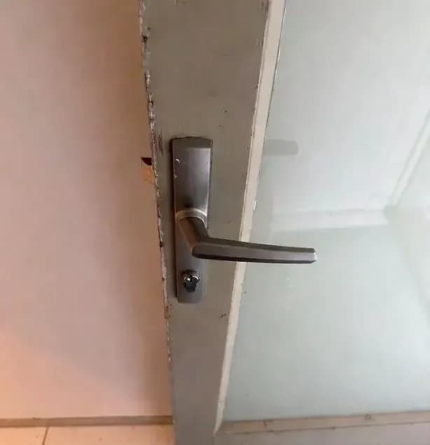 An old lever and cylinder plate on a white door, before the smart lock