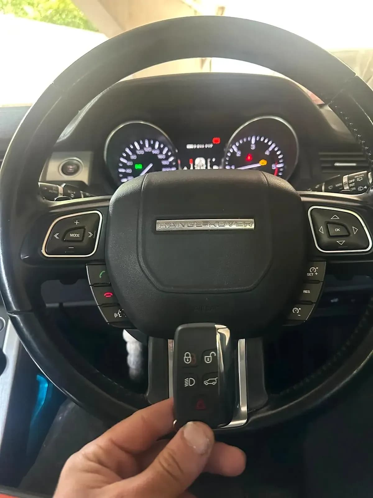 A Range Rover smart key held in front of the steering wheel of a Range Rover Evoque