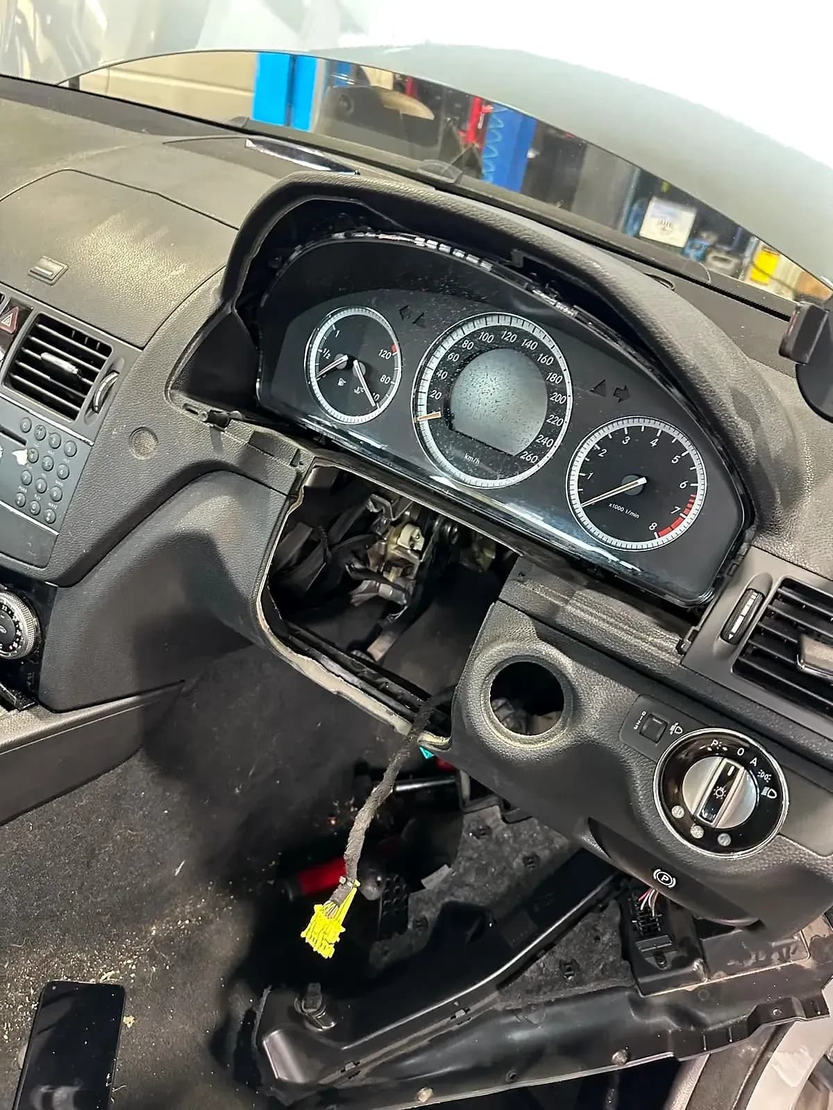 The dashboard of a Mercedes-Benz C-Class opened up, the instrument cluster lifted out and the column trim removed